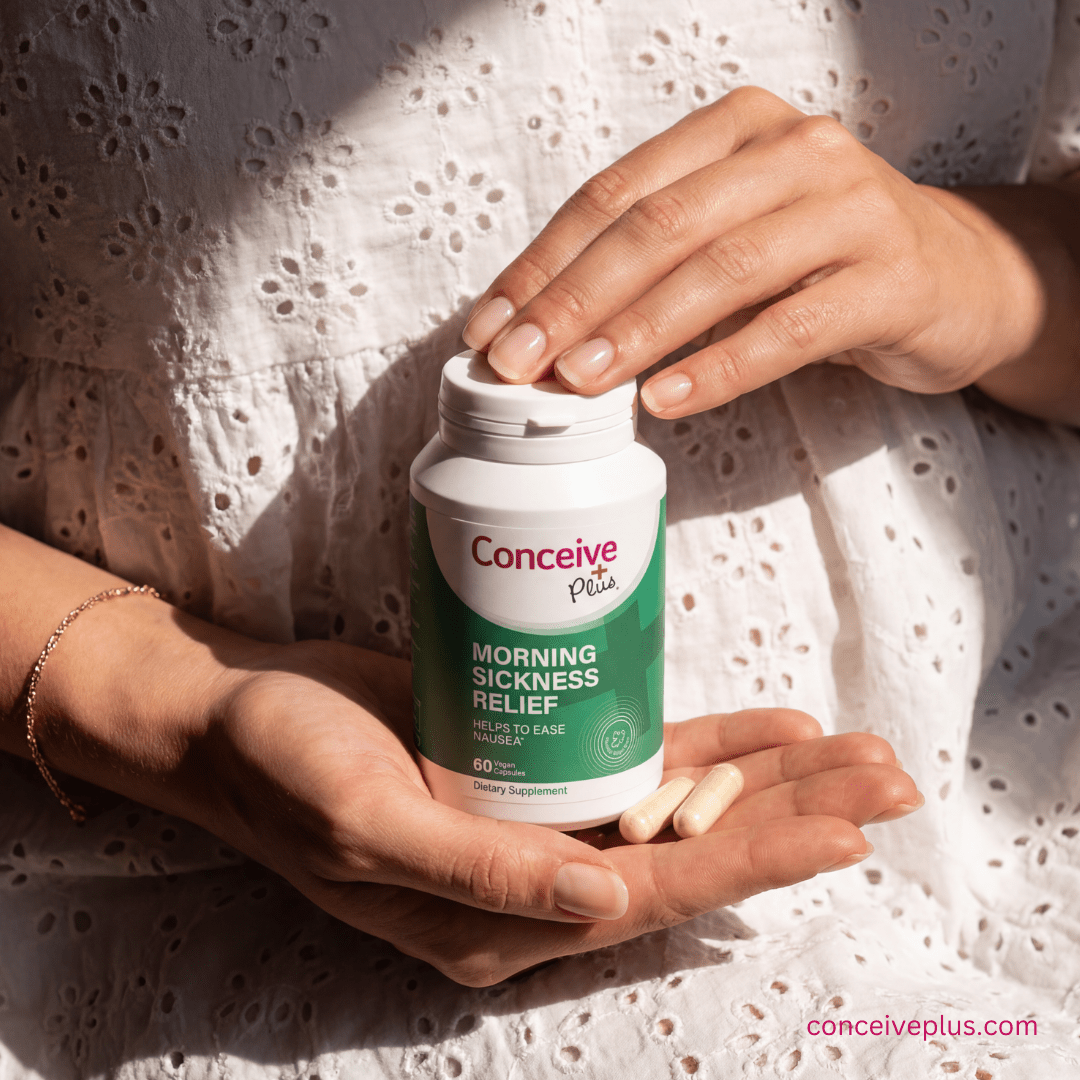 Person holding a bottle of Conceive Plus morning sickness relief supplement with pills in their hand.