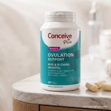 Supplement bottle labeled 'Conceive Plus Women's Ovulation Support' on a marble surface.