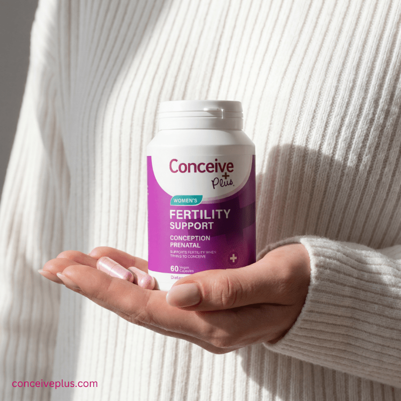 Person holding a bottle of Conceive Plus Fertility Support supplements.